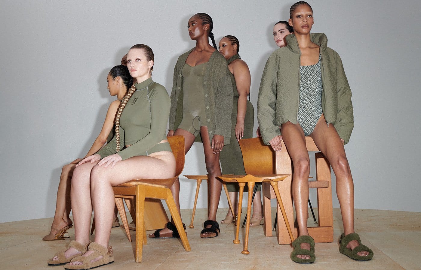Modelos sentadas usando peças Skims x Fendi combinadas com roupas externas em editorial de estúdio.